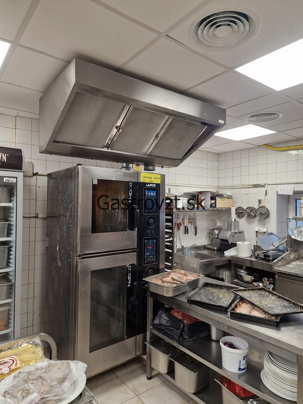 Veľký nerezový gastro digestor nad profesionálnym spotrebičom v kuchyni